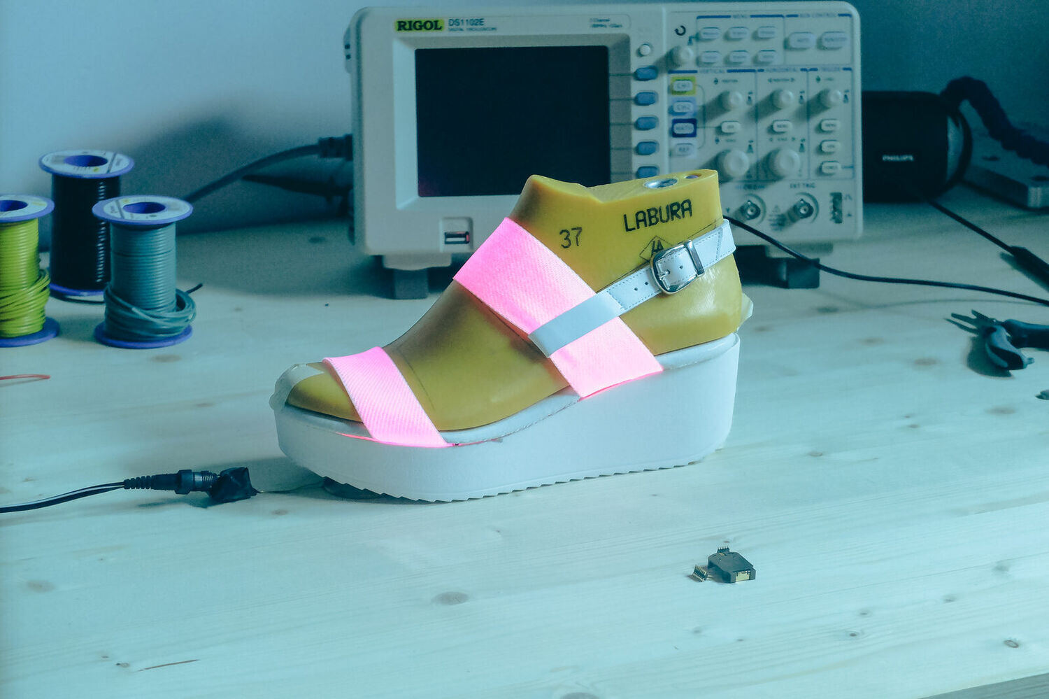 La sandale allumée en rose à côté d'un oscilloscope