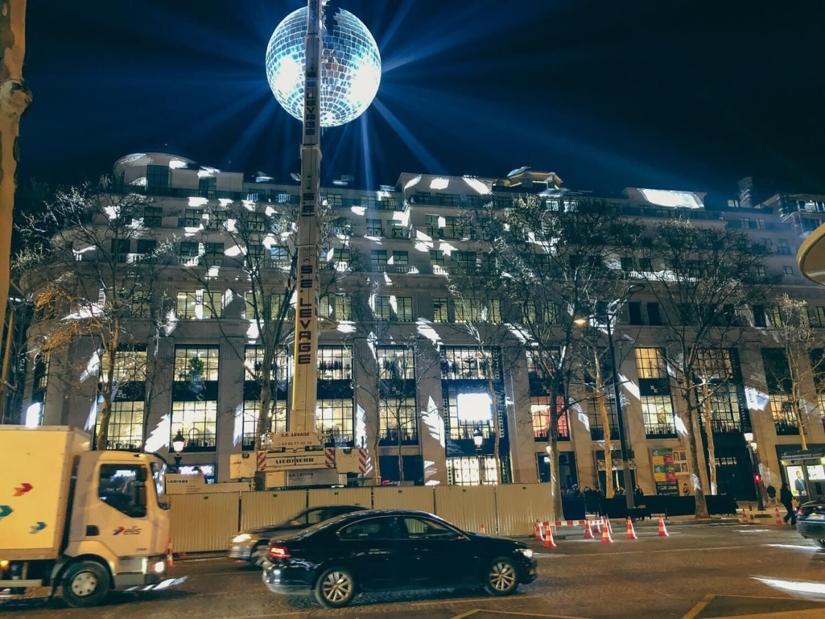 Une boule à facettes portée par une grue au-dessus des Champs-Élysées, le soir de l'inauguration