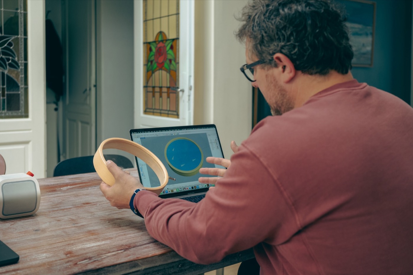 Le designer produit tient le cerclage en bois de l'horloge devant son modèle 3D